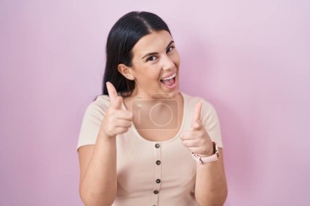Photo for Young hispanic woman standing over pink background pointing fingers to camera with happy and funny face. good energy and vibes. - Royalty Free Image