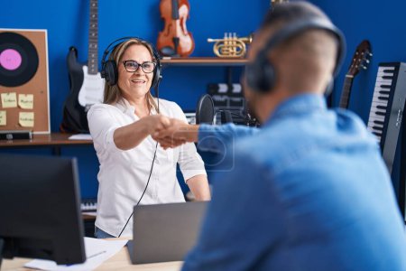 Photo for Man and woman musicians listening to music shake hands at music studio - Royalty Free Image
