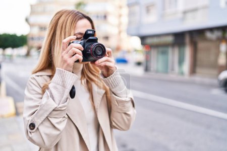 Foto de Young blonde woman susing professional camera at street - Imagen libre de derechos
