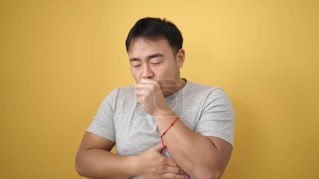 Photo for Young chinese man coughing over isolated yellow background - Royalty Free Image