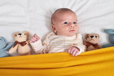 Téléchargez les photos : Adorable caucasian baby lying on bed with dolls at bedroom - en image libre de droit