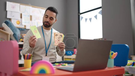 Photo for Young hispanic man working as teacher teaching online words lesson at kindergarten - Royalty Free Image
