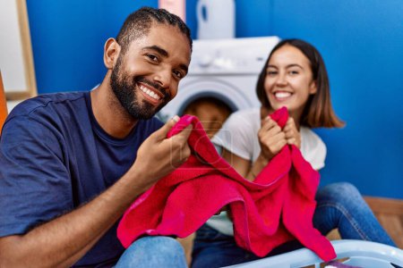Téléchargez les photos : Man and woman couple smelling towel washing clothes at laundry - en image libre de droit