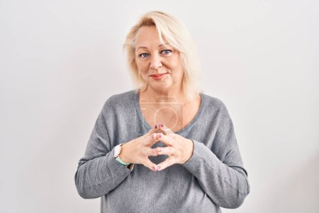 Téléchargez les photos : Middle age caucasian woman standing over white background hands together and fingers crossed smiling relaxed and cheerful. success and optimistic - en image libre de droit