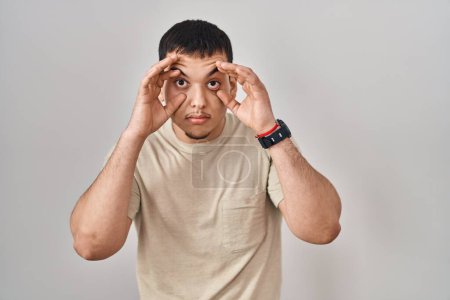 Téléchargez les photos : Jeune homme arabe portant t-shirt décontracté essayant d'ouvrir les yeux avec les doigts, somnolent et fatigué pour la fatigue matinale - en image libre de droit