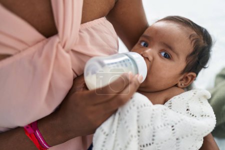 Téléchargez les photos : Africain américain bébé sucer biberon d'alimentation à chambre - en image libre de droit