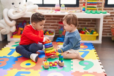Foto de Dos niños jugando con aros de juguete sentado en el suelo en el jardín de infantes - Imagen libre de derechos