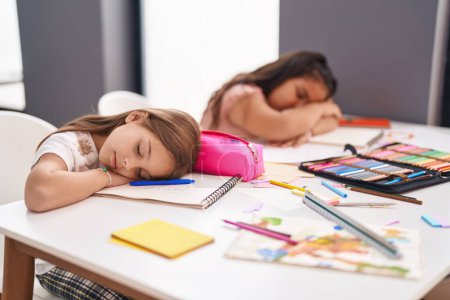 Téléchargez les photos : Deux enfants étudiants assis sur la table dormant en classe - en image libre de droit