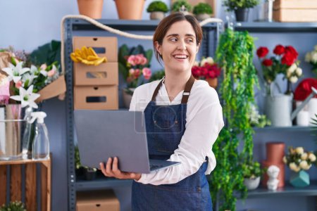 Photo for Young woman florist smiling confident using laptop at florist shop - Royalty Free Image