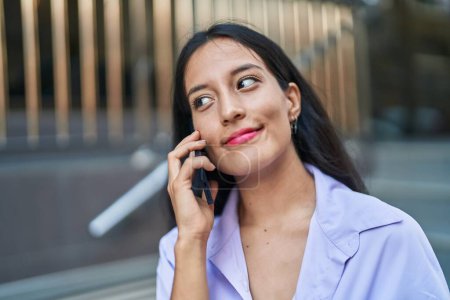 Téléchargez les photos : Jeune belle femme hispanique souriant confiant parler sur le smartphone à la rue - en image libre de droit
