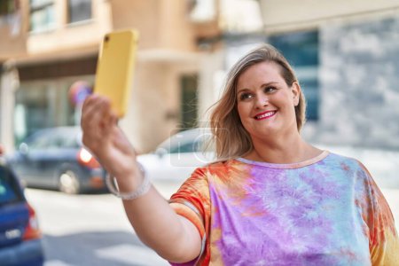 Foto de Young woman smiling confident making selfie by the smartphone at street - Imagen libre de derechos