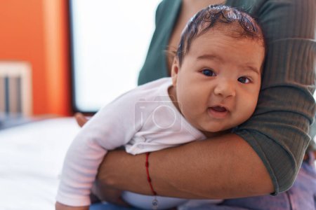 Téléchargez les photos : Adorable bambin hispanique sur les bras de la mère à la maison - en image libre de droit