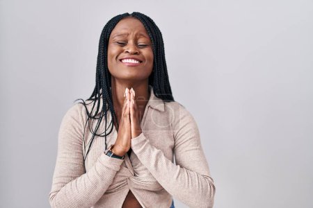 Photo for African woman with braids standing over white background begging and praying with hands together with hope expression on face very emotional and worried. begging. - Royalty Free Image