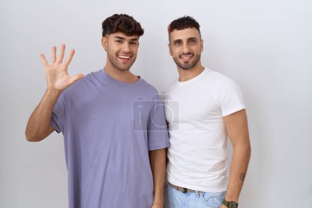 Téléchargez les photos : Couple gay homosexuel debout sur fond blanc montrant et pointant vers le haut avec les doigts numéro cinq tout en souriant confiant et heureux. - en image libre de droit