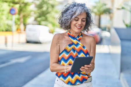 Téléchargez les photos : Middle age grey-haired woman smiling confident using touchpad at street - en image libre de droit