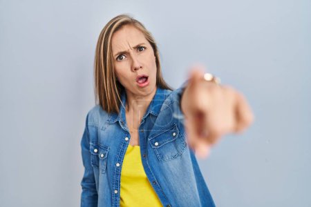 Photo for Young blonde woman standing over blue background pointing displeased and frustrated to the camera, angry and furious with you - Royalty Free Image