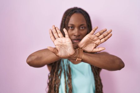 Téléchargez les photos : Femme afro-américaine debout sur fond rose expression de rejet croisant les bras et les paumes faisant signe négatif, visage en colère - en image libre de droit