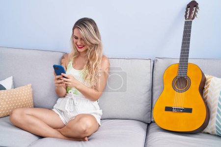 Photo for Young beautiful hispanic woman using smartphone sitting on sofa at home - Royalty Free Image