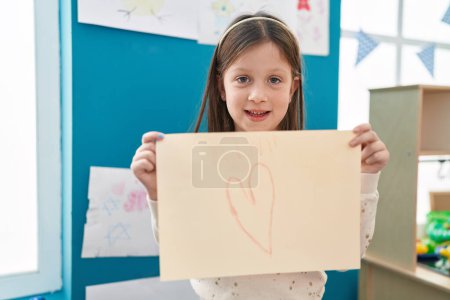 Photo for Adorable hispanic girl preschool student holding heart draw at kindergarten - Royalty Free Image