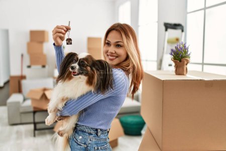 Photo for Young caucasian woman smiling confident holding key and dog at new home - Royalty Free Image