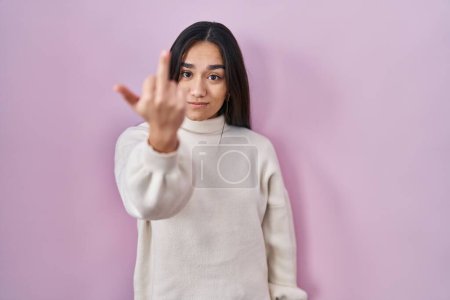 Foto de Young south asian woman standing over pink background showing middle finger, impolite and rude fuck off expression - Imagen libre de derechos