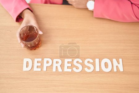 Photo for Young beautiful hispanic woman business worker sitting on table with depression word and glass of whisky at office - Royalty Free Image