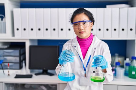 Foto de Mujer asiática joven que trabaja en el laboratorio científico escéptico y nervioso, frunciendo el ceño molesto debido a un problema. persona negativa. - Imagen libre de derechos