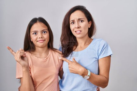 Téléchargez les photos : Young mother and daughter standing over white background pointing aside worried and nervous with forefinger, concerned and surprised expression - en image libre de droit