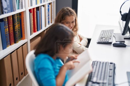 Photo for Two kids students using computer reading book at classroom - Royalty Free Image