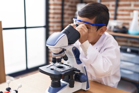 Téléchargez les photos : Adorable élève hispanique garçon en utilisant le microscope à la salle de classe de laboratoire - en image libre de droit