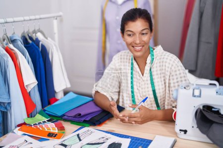 Photo for Young beautiful hispanic woman tailor smiling confident speaking at tailor shop - Royalty Free Image
