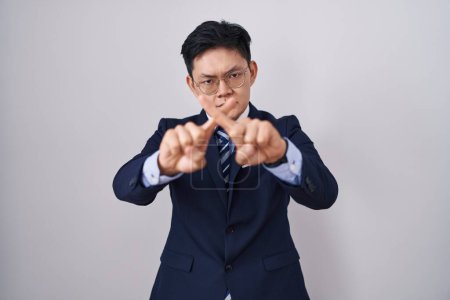 Photo for Young asian man wearing business suit and tie rejection expression crossing fingers doing negative sign - Royalty Free Image
