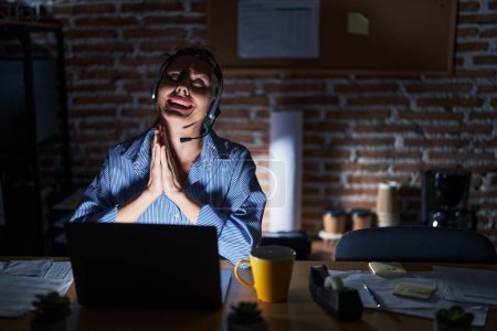 Photo for Beautiful brunette woman working at the office at night begging and praying with hands together with hope expression on face very emotional and worried. begging. - Royalty Free Image