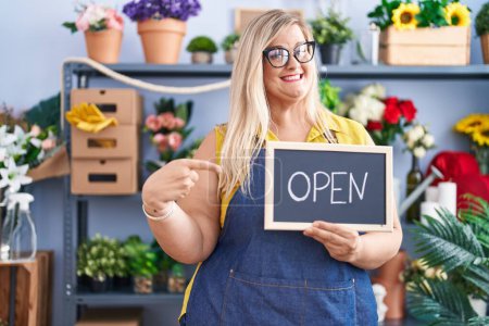 Photo for Caucasian plus size woman working at florist holding open sign smiling happy pointing with hand and finger - Royalty Free Image