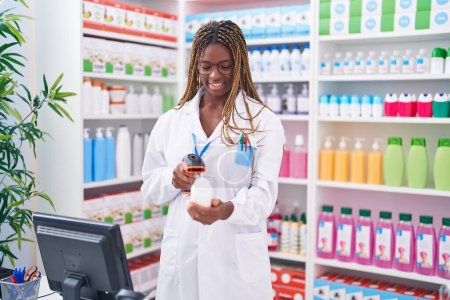 Foto de Botella de pastillas de escaneo de farmacéutica afroamericana en farmacia - Imagen libre de derechos