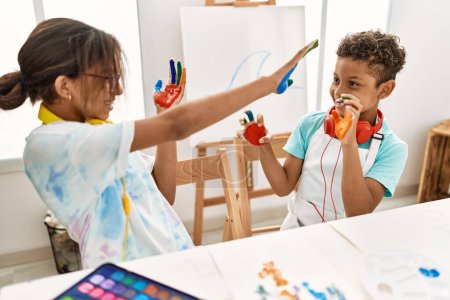 Téléchargez les photos : Frère et sœur portant des écouteurs jouant avec des mains de paume peintes au studio d'art - en image libre de droit