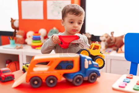 Téléchargez les photos : Adorable garçon hispanique jouant avec camion jouet à la maternelle - en image libre de droit