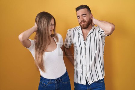 Téléchargez les photos : Young couple standing over yellow background suffering of neck ache injury, touching neck with hand, muscular pain - en image libre de droit