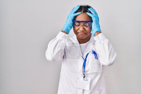 Photo for African american woman with braids wearing scientist robe suffering from headache desperate and stressed because pain and migraine. hands on head. - Royalty Free Image