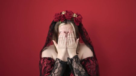 Téléchargez les photos : Jeune femme blonde portant katrina costume faisant expression de peur sur fond rouge isolé - en image libre de droit