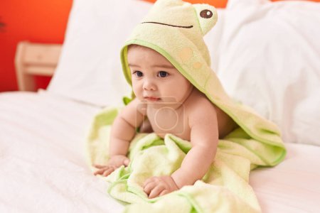 Photo for Adorable hispanic toddler wearing funny towel sitting on bed at bedroom - Royalty Free Image