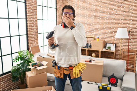Photo for Handsome middle age man holding screwdriver at new home shocked covering mouth with hands for mistake. secret concept. - Royalty Free Image