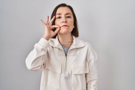 Photo for Middle age hispanic woman standing over isolated background mouth and lips shut as zip with fingers. secret and silent, taboo talking - Royalty Free Image