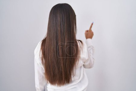 Foto de Young brunette woman wearing glasses posing backwards pointing ahead with finger hand - Imagen libre de derechos