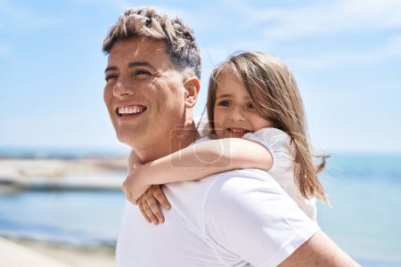 Foto de Padre e hija sonriendo confiados abrazándose unos a otros sosteniéndose en la orilla del mar - Imagen libre de derechos