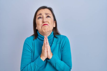 Photo for Middle age hispanic woman standing over isolated background begging and praying with hands together with hope expression on face very emotional and worried. begging. - Royalty Free Image