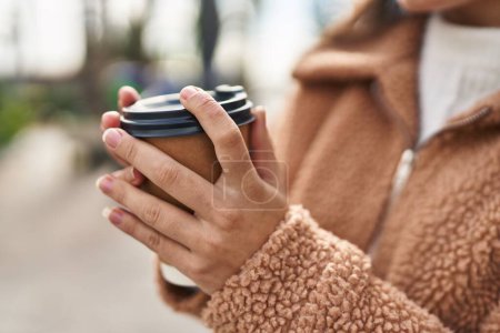 Téléchargez les photos : Young hispanic woman drinking coffee at street - en image libre de droit