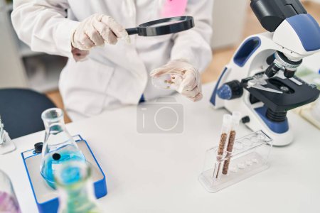 Photo for Young chinese woman wearing scientist uniform using loupe at laboratory - Royalty Free Image