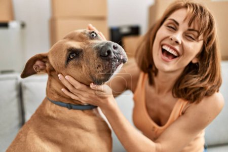 Photo for Young caucasian woman hugging dog sitting on sofa at home - Royalty Free Image