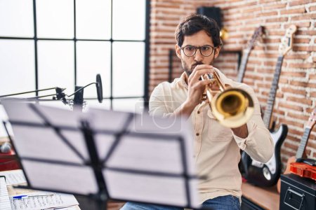 Téléchargez les photos : Young hispanic man musician playing trumpet at music studio - en image libre de droit